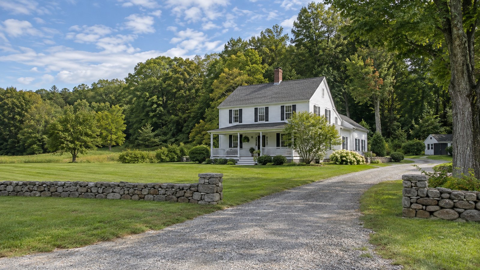 Review the whole property A whole white clapboard farmhouse with a front porch, gravel driveway and low stone walls.